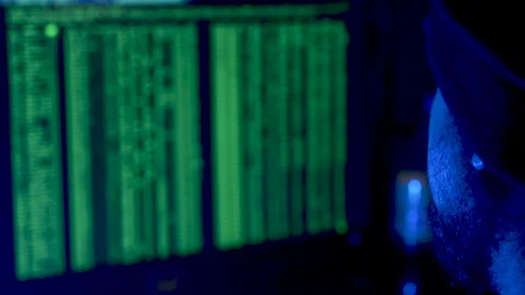 Computer hacker in front of a screen displaying computer code Stock Footage 282174824