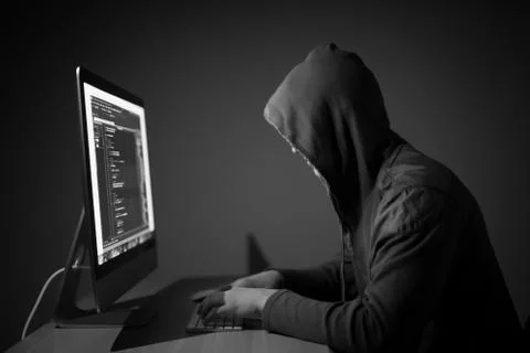 Computer hacker in hood working in dark room code on pc and hack networks 스톡 사진