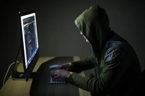 Computer hacker in hood working in dark room code on pc and hack networks 스톡 사진