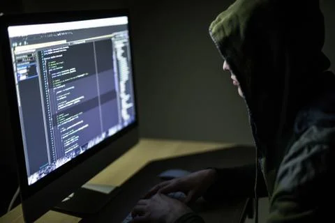 Computer hacker in hood working in dark room code on pc and hack networks Foto stock