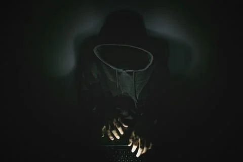 Computer hacker with a laptop in darkness 库存照片