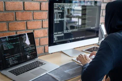 Computer hacker or cyber attack concept, Dangerous hooded hacker using multip 库存照片