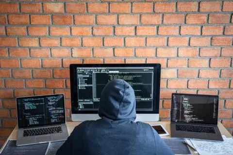 Computer hacker or cyber attack concept, Dangerous hooded hacker using multip Stock Photos