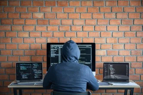 Computer hacker or cyber attack concept, Dangerous hooded hacker using multip Stock Photos