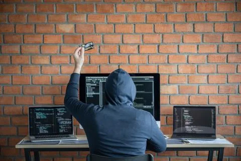 Computer hacker or cyber attack concept, Dangerous hooded hacker using multip Stock Photos