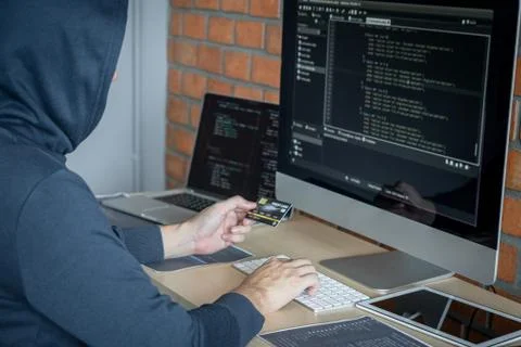 Computer hacker or cyber attack concept, Dangerous hooded hacker using multip 库存照片