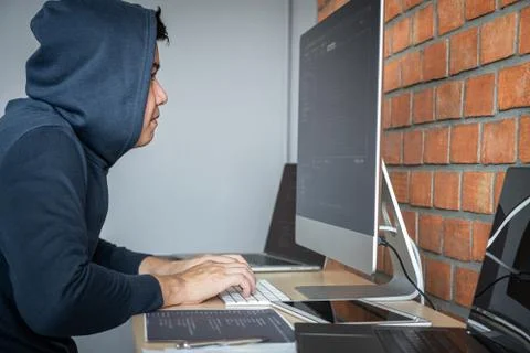 Computer hacker or cyber attack concept, Dangerous hooded hacker using multip Foto stock