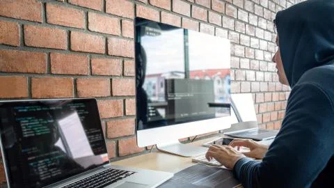 Computer hacker or cyber attack concept, Dangerous hooded hacker using multip Stock Photos