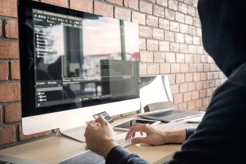 Computer hacker or cyber attack concept, Dangerous hooded hacker using multip 库存照片