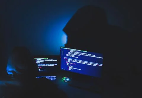 Computer hacker silhouette of hooded, man using laptop and monitor for steal Foto stock