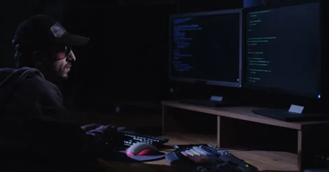 Computer hacker sitting in front of screens in a dark room Stock Footage 68294476