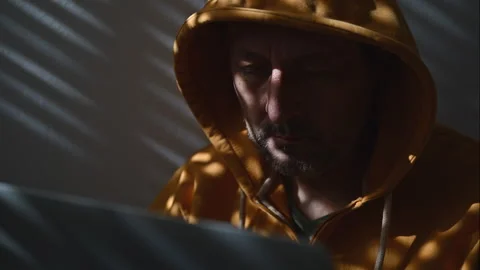 Computer hacker wearing yellow hoodie using laptop, 4K Stock Footage 288593875