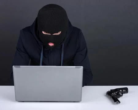 Computer hacking. Angry young men in balaclava gesturing and looking at the comp 写真素材