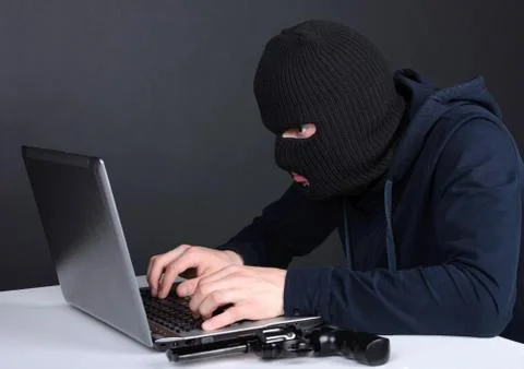 Computer hacking. Angry young men in balaclava gesturing and looking at the comp 스톡 사진
