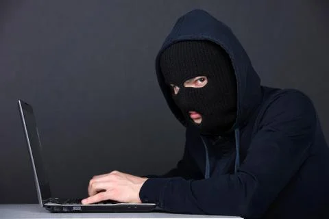 Computer hacking. Angry young men in balaclava gesturing and looking at the comp Stock Photos