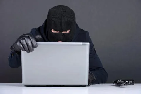 Computer hacking. Angry young men in balaclava gesturing and looking at the comp Stock Photos