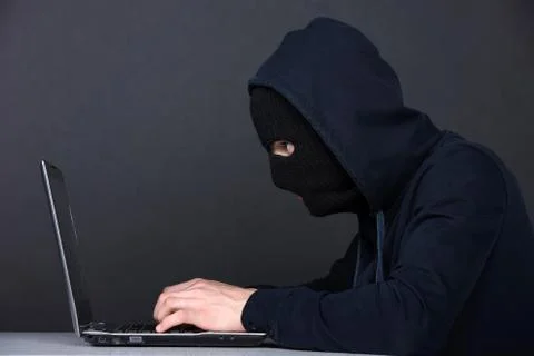 Computer hacking. Angry young men in balaclava gesturing and looking at the comp 스톡 사진