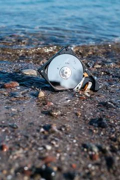 Computer hard disk lies in the shore sand of the sea and is washed by the wat Foto stock