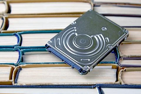Computer hard drive on the background of a pile of old paper books 스톡 사진