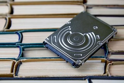 Computer hard drive on the background of a stack of old paper books Stock Photos