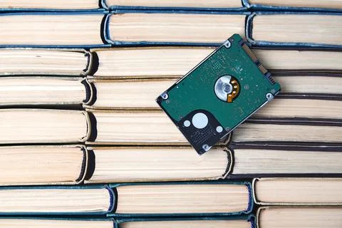 Computer hard drive on the background of a stack of old paper books. Comparison 스톡 사진