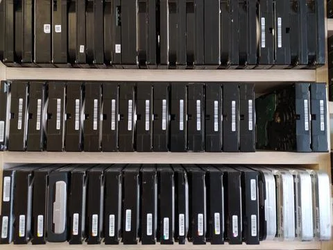 Computer hard drives stand in neat rows on shelves in a computer repair shop. Stock Photos