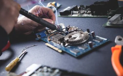 Computer hardware engineering. Engineer soldering computer motherboard Stock Photos