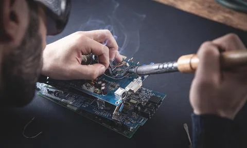 Computer hardware engineering. Engineer soldering computer motherboard Stock Photos