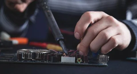 Computer hardware engineering. Engineer soldering computer motherboard Stock Photos