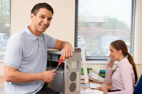 Computer IT Support Worker Fixing Machine In Office Stock Photos