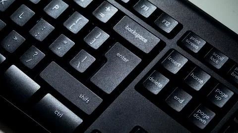 Computer key in macro with Enter key on keyboard with light shining on keys. Stockfoto's