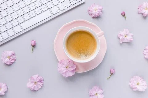 Computer keyboard and coffee on on spring pink background with flowers Stock Photos