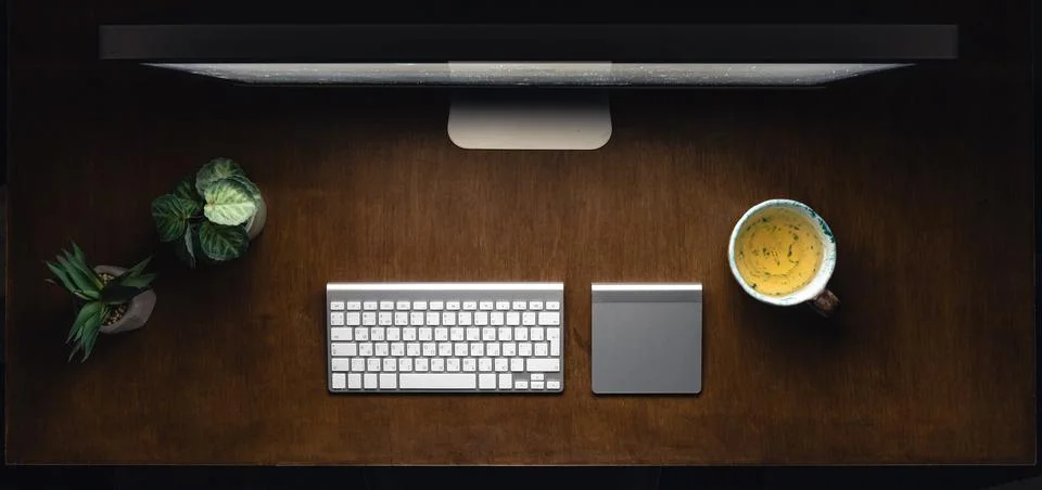 Computer, keyboard and cup of tea on a wooden table at night. Stock Photos