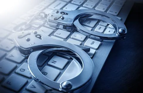Computer keyboard and handcuffs Stock Photos