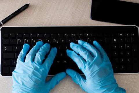Computer keyboard and hands in protective gloves 写真素材