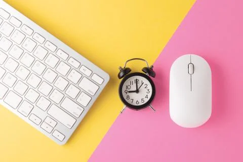 Computer keyboard and mouse with clock on yellow pink background, minimal, fl Stock Photos