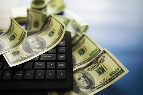 Computer keyboard and a scattering of 100 dollar bills on the table. The wo.. Stock Photos