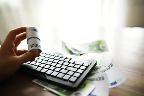 Computer keyboard and a scattering of 100 euro bills on the table. The work.. Stock Photos