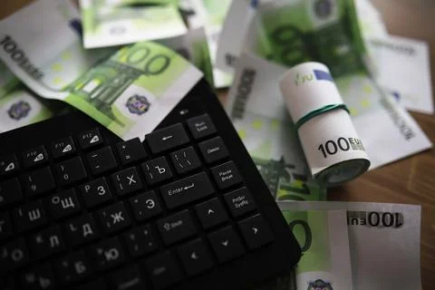 Computer keyboard and a scattering of 100 euro bills on the table. The work.. Stockfoto's