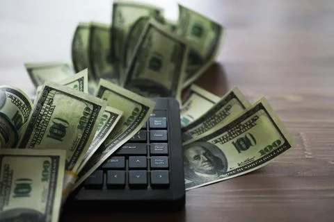 Computer keyboard and a scattering of 100 dollar bills on the table. The wo.. Stock Photos