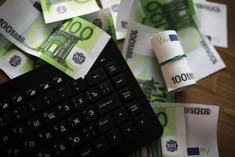 Computer keyboard and a scattering of 100 euro bills on the table. The work.. Stock Photos
