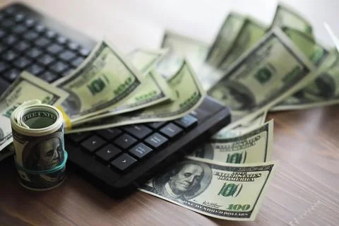 Computer keyboard and a scattering of 100 dollar bills on the table. The wo.. Stockfoto's