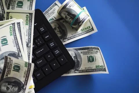 Computer keyboard and a scattering of 100 dollar bills on the table. The wo.. Stock Photos