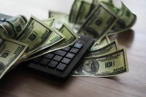 Computer keyboard and a scattering of 100 dollar bills on the table. The wo.. Stock Photos