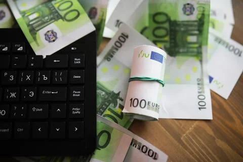 Computer keyboard and a scattering of 100 euro bills on the table. The work.. Stock Photos