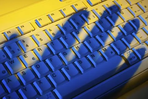 Computer keyboard and the shadow of a hand. Theft of data. Austria 写真素材