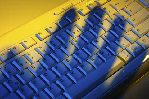 Computer keyboard and the shadow of a hand. Theft of data. Austria Stockfoto's