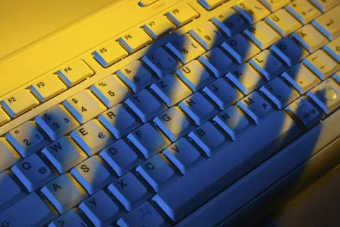 Computer keyboard and the shadow of a hand. Theft of data. Austria Stock Photos