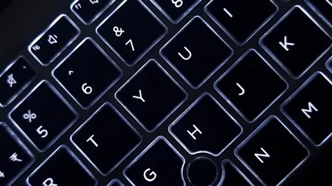 Computer keyboard backlit lights illuminating in letter symbols, dark background Stockbeeldmateriaal 257818200
