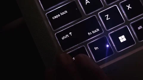 Computer keyboard backlit lights illuminating in letter symbols, dark background Stock Footage 257818218